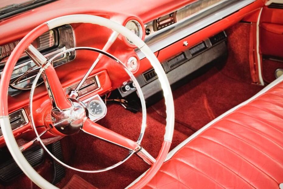 Here's a close-up shot of a classic car's interior. The car has red leather upholstery and a red-and-white steering wheel.